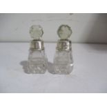 A pair of small scent bottles with hallmarked silver collars