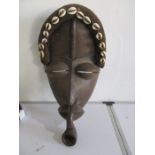 An African mask of a man smoking a pipe decorated with shells