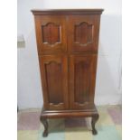 A mahogany cabinet with four doors, filing shelves in top compartment and drawer under- keys in