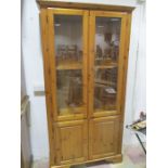 A pine display cabinet with cupboard under