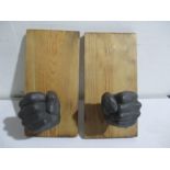 A pair of metal candle holders in the form of fists, mounted on pine boards