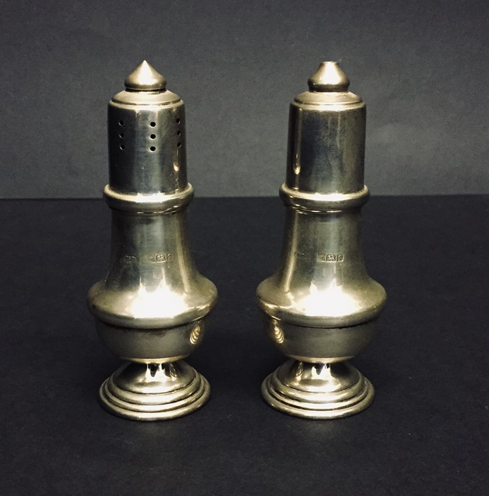 A cased pair of hallmarked silver salt and pepper shakers.