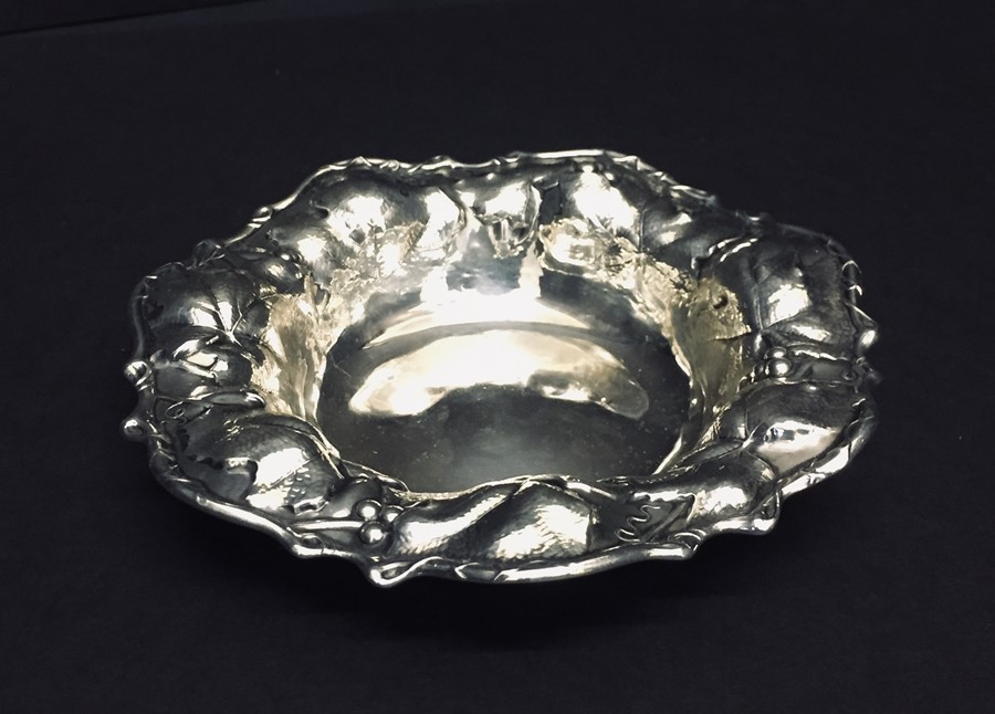 A sterling silver bon bon dish decorated with leaves and berries.