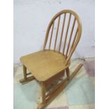 A blonde Ercol stick back rocking chair with drawer under