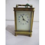 A brass carriage clock with white face enamelled dial