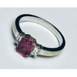 An 18ct white gold ring set with an emerald cut pink sapphire and two baguette diamonds.