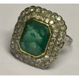 A good emerald and diamond cluster ring set in unmarked white gold, the central emerald measuring