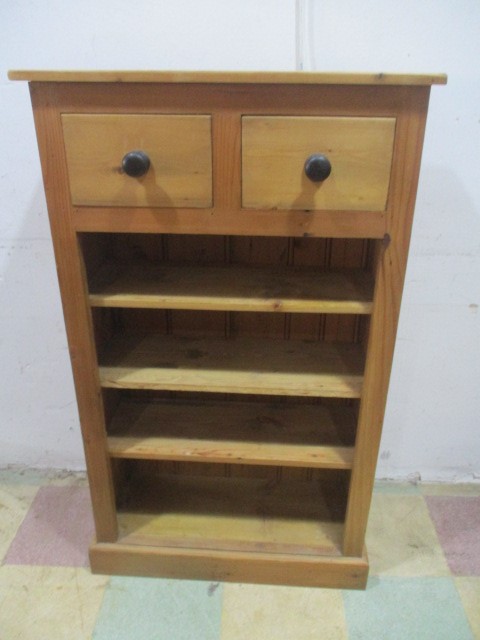 A set of freestanding pine shelves with two drawers above