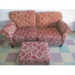 An upholstered two seater sofa with a matching foot stool