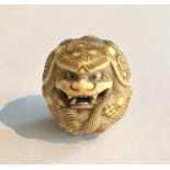 An ivory Netsuke carved as a dragon holding the pearl of wisdom in its mouth- unsigned