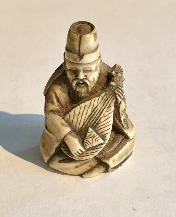 A 19th Century ivory Netsuke of a seated man playing the lute