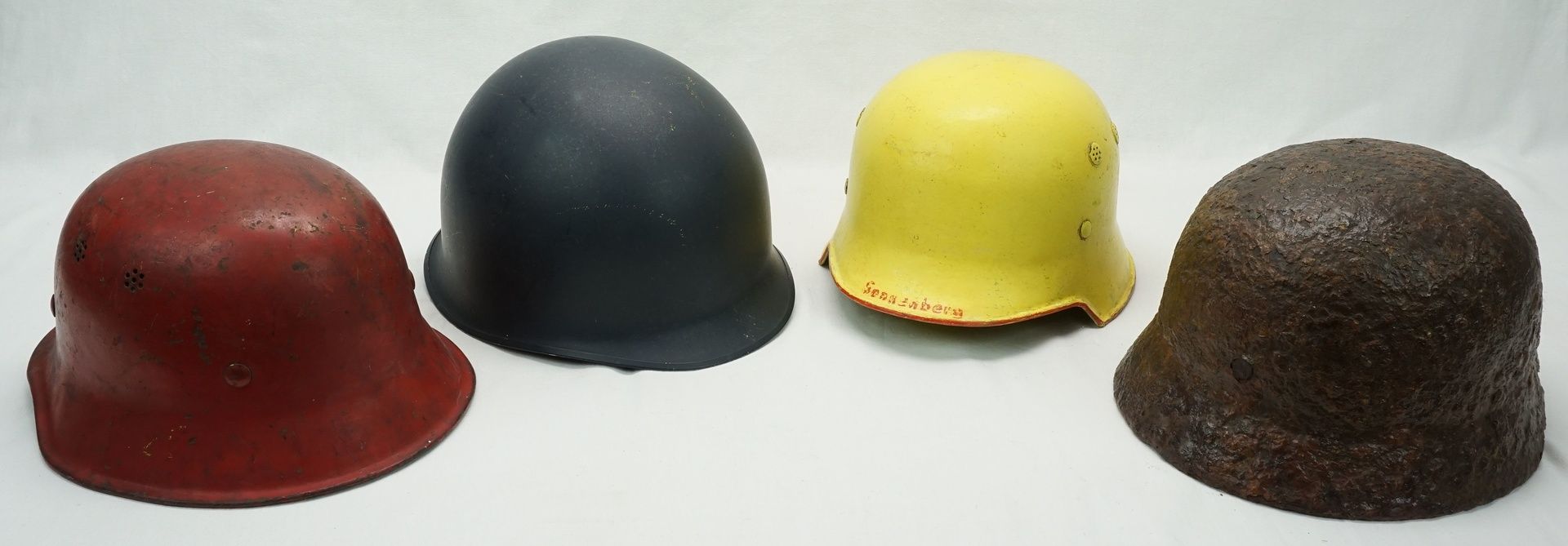 Vier Stahlhelme, 1. Hälfte 20. Jh.1) Feuerwehrhelm, rot lackiert, mit Innenleben, 2)