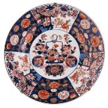A large Japanese Arita Imari charger, decorated in the centre with a flower basket and roundels with