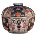 A large Japanese Arita Imari covered bowl, decorated with panels filled with a vase in a garden sett