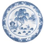 A large Chinese deep charger, blue and white decorated with figures in a garden near a willow tree,