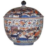 A large Japanese Arita Imari covered bowl, decorated with a pavilion in garden setting, with flower