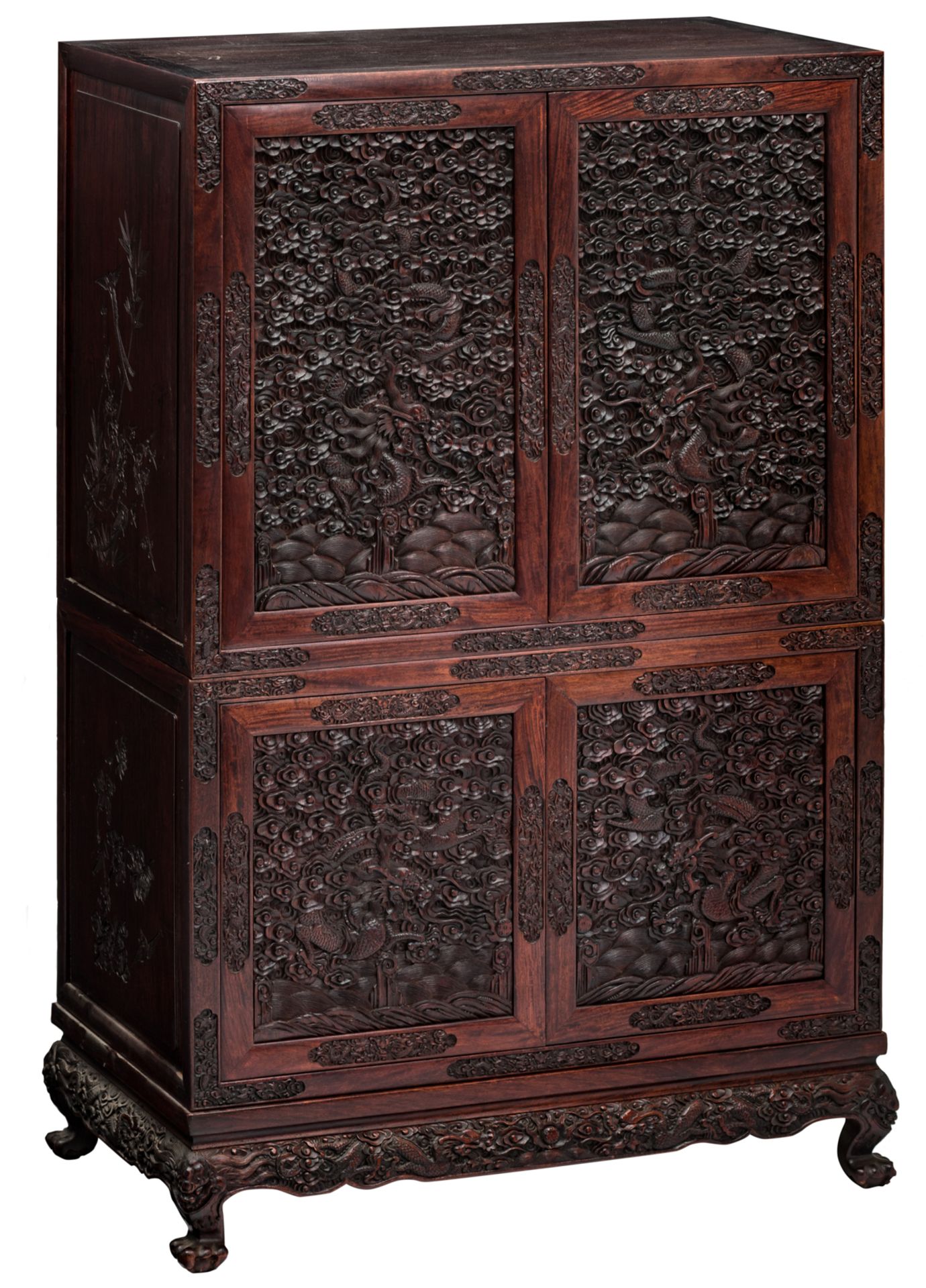 An Oriental four door cabinet in exotic hardwood, the doors sculpted with dragons amongst clouds, th