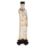 An ivory statue, depicting a Chinese scholar on a sculpted wooden base, with an engraved and black c