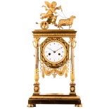 A neoclassical pendulum clock decorated on top with a cupid riding a chariot pulled by a sheep,