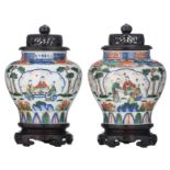 Two Chinese wucai floral decorated vases and hardwood covers, the roundels with animated scenes,