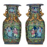 A pair of Chinese blue ground famille rose vases with gilt relief decoration, the panels with