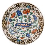 An Iznik pottery dish, the central part floral decorated in cobalt blue, green and red, with black