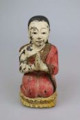 Kniender Buddha auf Sockel, Holz, Südostasien, 19./ 20. Jh., polychrome Bemalung, H: ca. 40 cm,