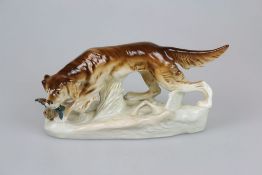 Porzellanfigur, Jagdhund/Setter mit Fasan im Maul, bunt staffiert, Boden mehrfach gemarkt, u.a. "