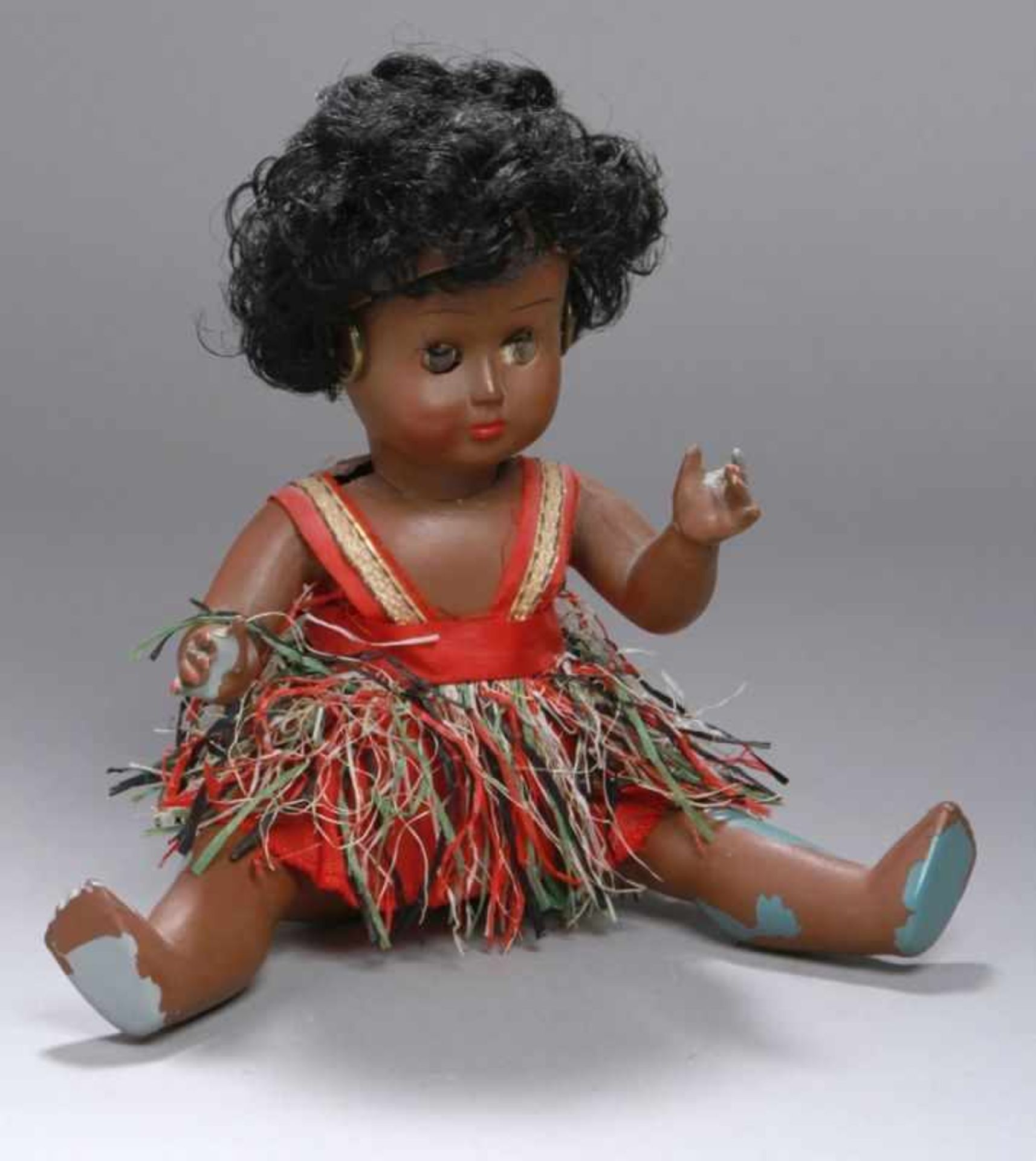 Puppe, dunkelhäutiges Mädchen, bekleidet mit Träger-Baströckchen, Kurbelkopf, feststehendebraune