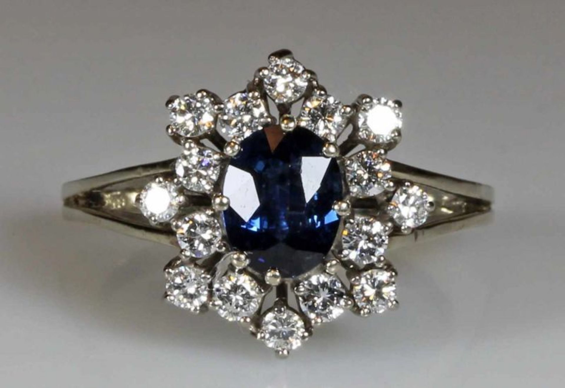 Ring, WG 585, 1 oval facettierter Saphir ca. 1.40 ct., 16 Brillanten zus. ca. 0.65 ct., alle etwa