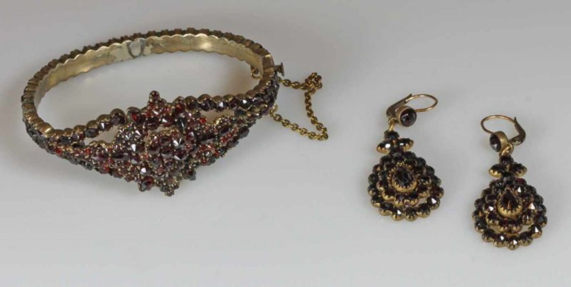 Granatschmuck, um 1900, Fassungen Metall: Armreif (ein Granat fehlt), Paar Ohrgehänge 25.00 %