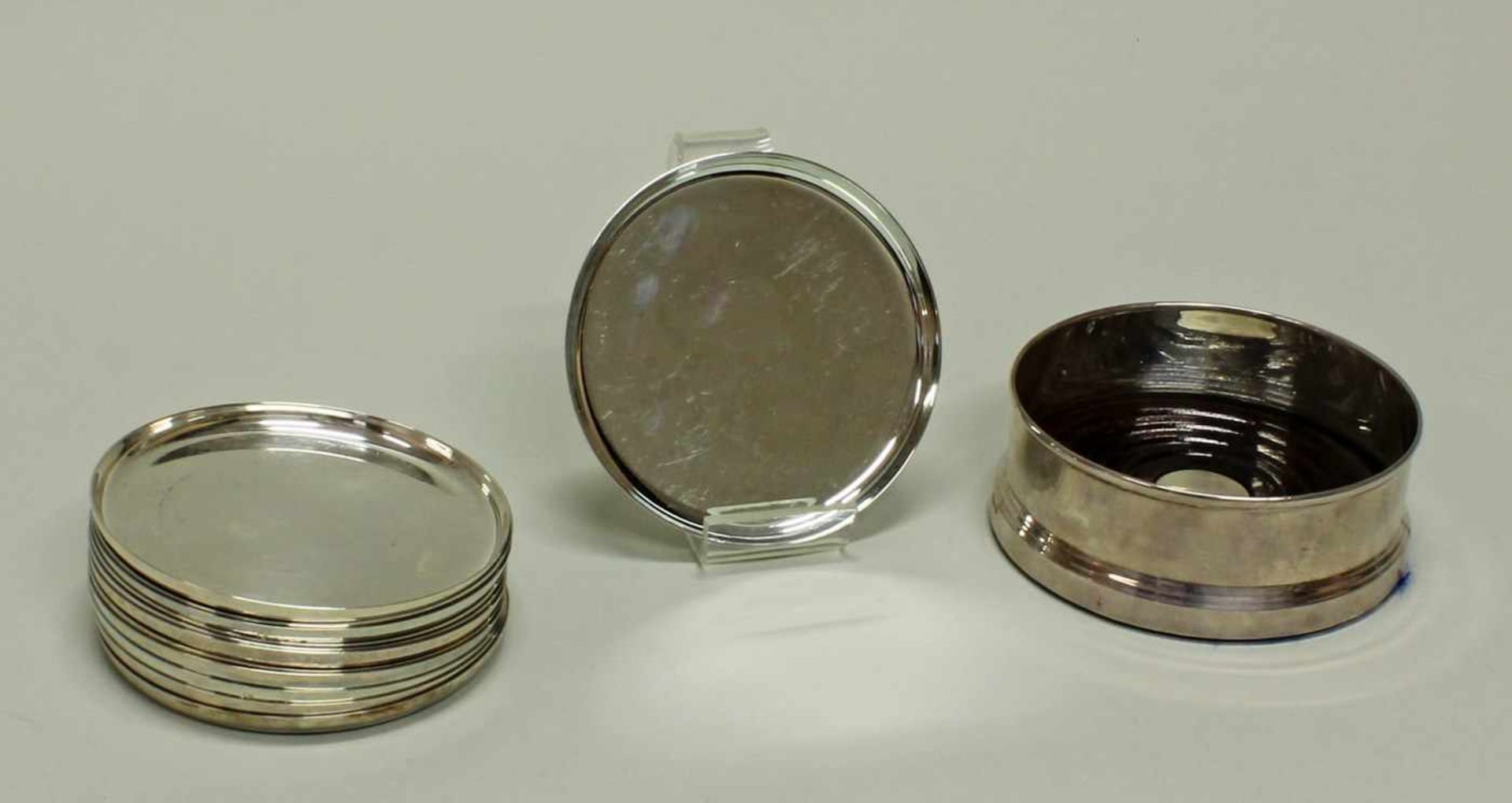 12 Untersetzer, Silber 925, Koch & Bergfeld, glatt, ø 10 cm, zus. ca. 922 g; Flaschenständer, Silber