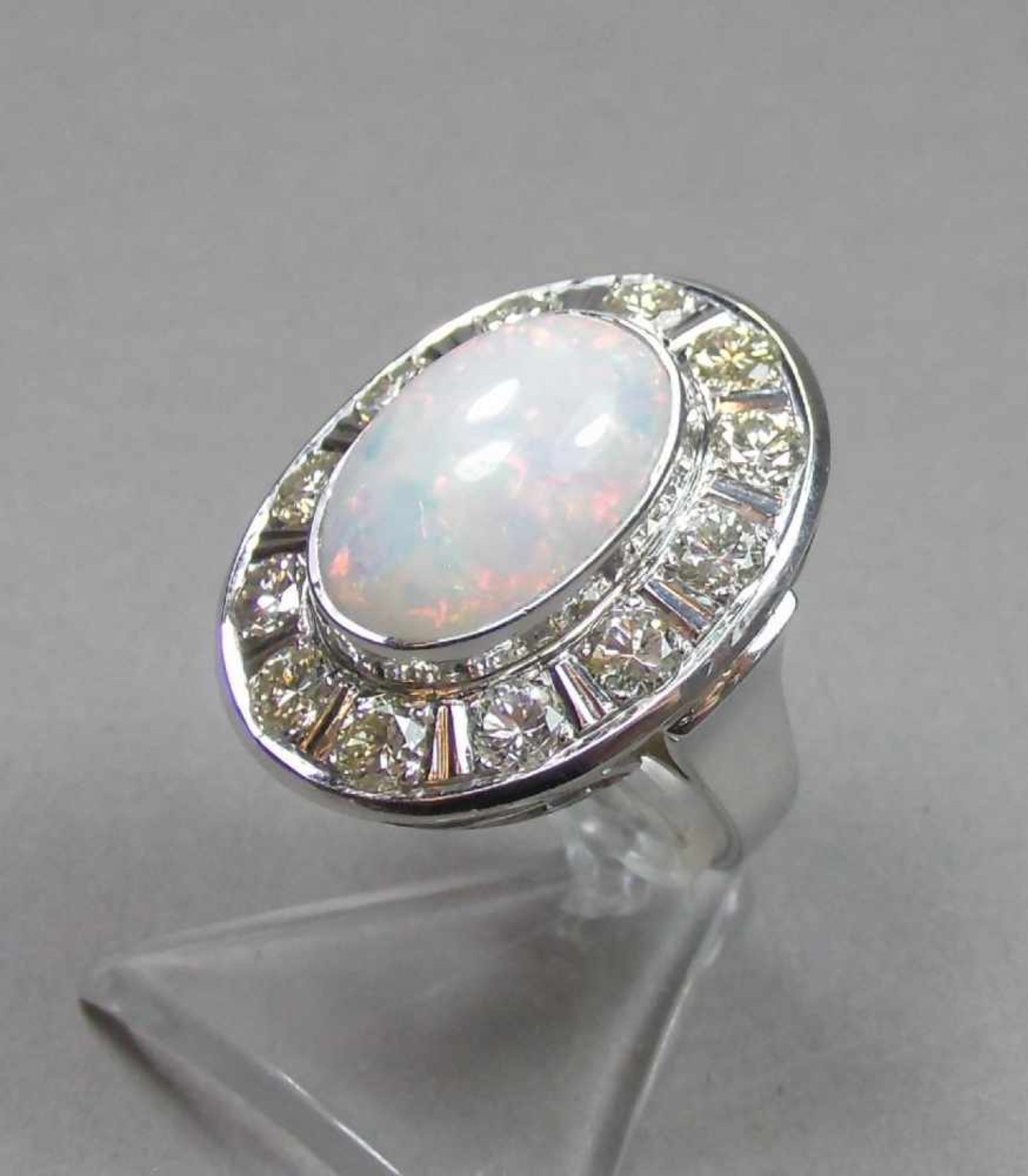 EXCLUSIVER RING mit weißem Opal im Cabochon-Schliff, umgeben von 12 Brillanten von je 0,2 kt. (