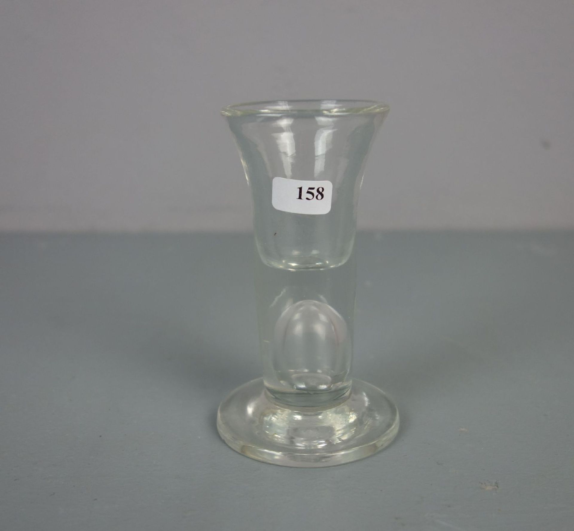 SCHNAPSGLAS, sog. KUTSCHERGLAS oder Fuhrmannspinnchen, 19. Jh., Klarglas mit Schlieren,