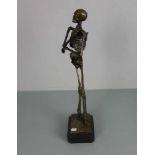 SKULPTUR "Rauchendes Skelett", Bronze, hellbraun patiniert und partiell farbig akzentuiert;