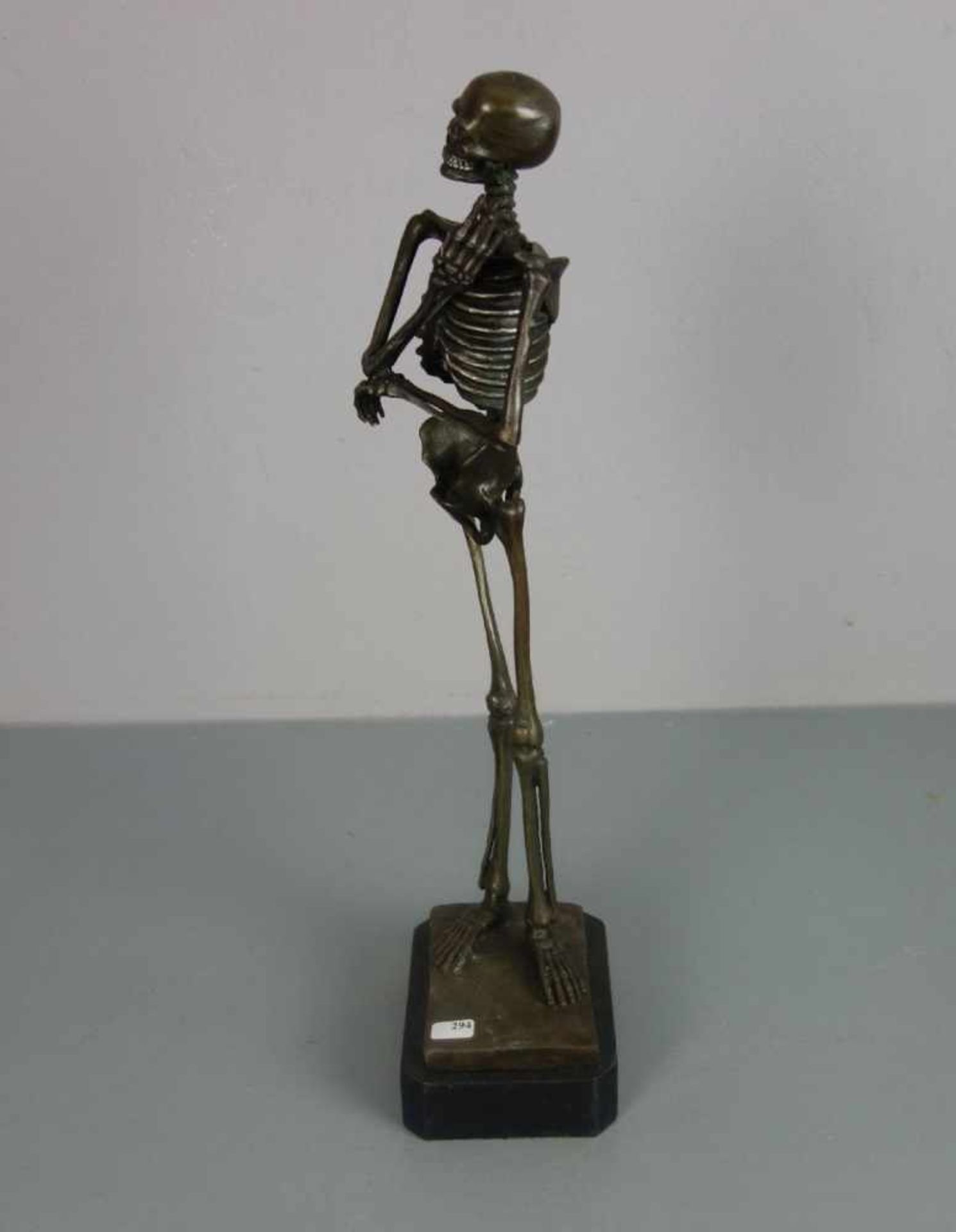 SKULPTUR "Rauchendes Skelett", Bronze, hellbraun patiniert und partiell farbig akzentuiert;