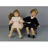 PUPPENPAAR AUF BANK, 2. H. 20. Jh.; Miniaturbank aus Holz und Metall; darauf sitzend zwei Puppen mit