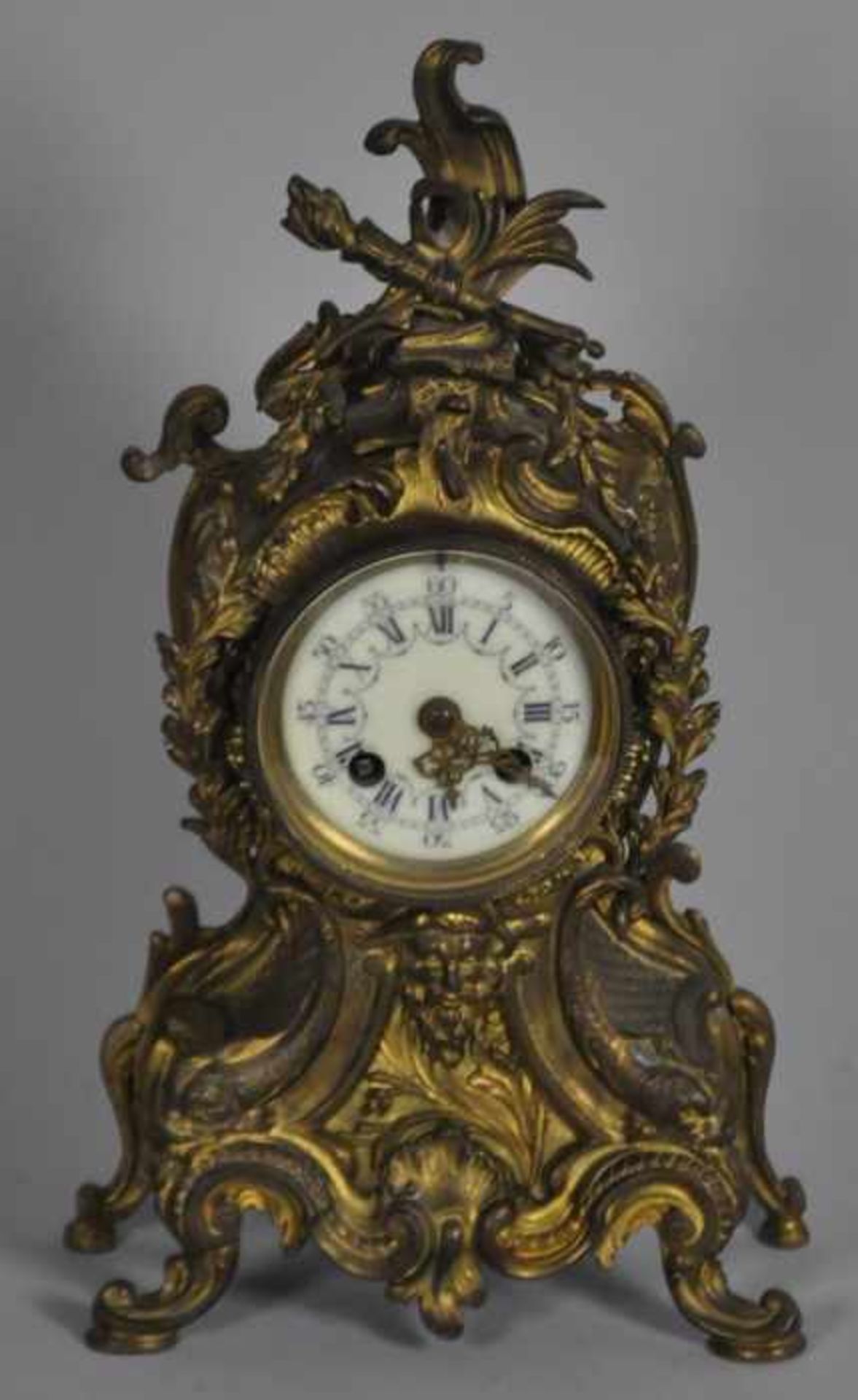 KAMINUHR reich dekorierter Stand, Metall vergoldet, altersbedingt leicht gedunkelt, darin Uhr mit