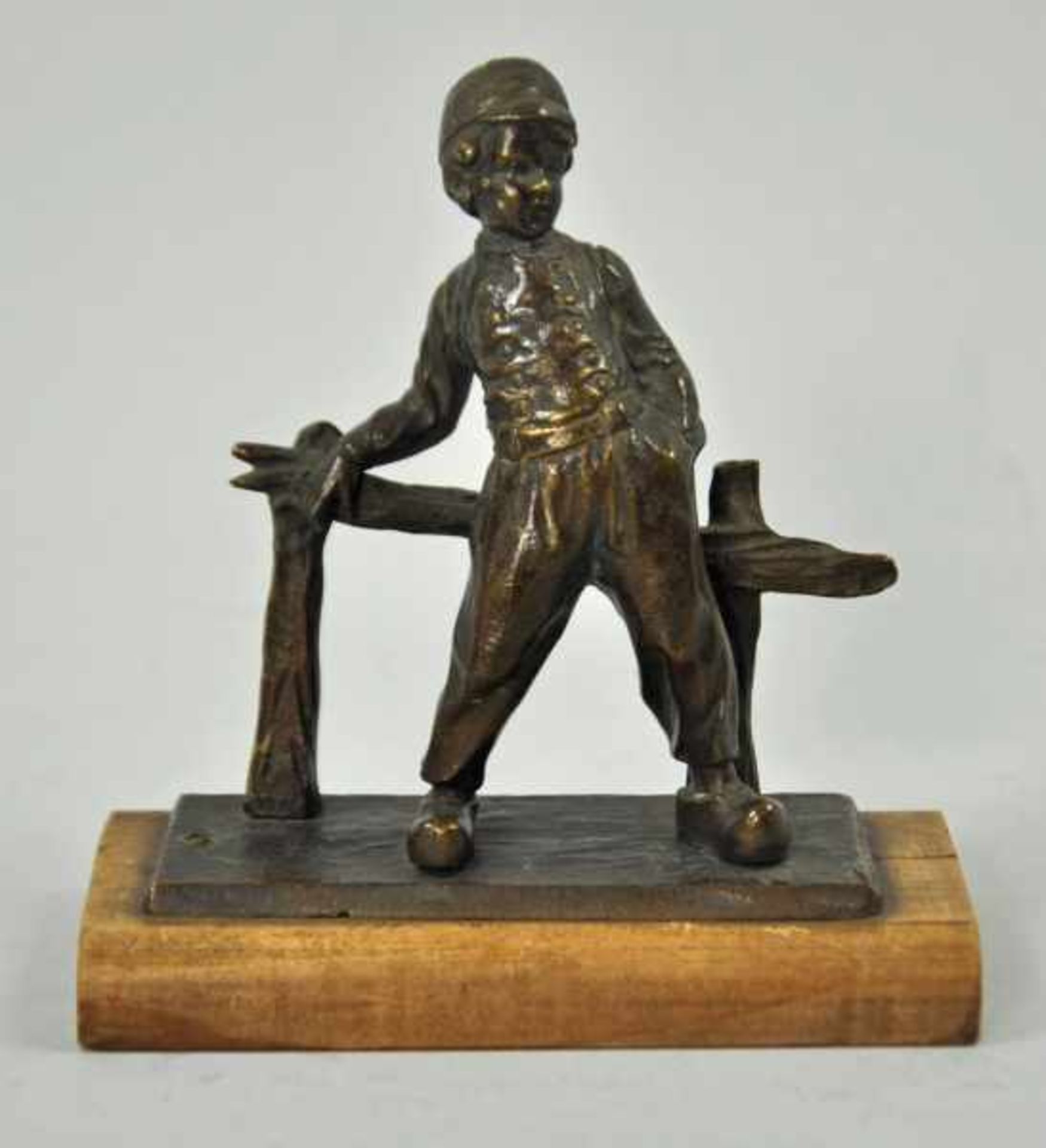 KLEINER JUNGE mit Münze, sich an Holzzaun anlehnend, Bronze patiniert, montiert auf Holzbasis, 19/