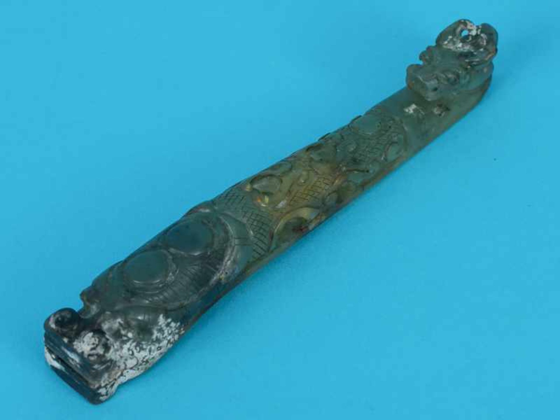 Jade-Gürtelschließe, China, 19. Jh. Grünfarbig variierte Jade, geschnitzt; in geschweifter Stabform,