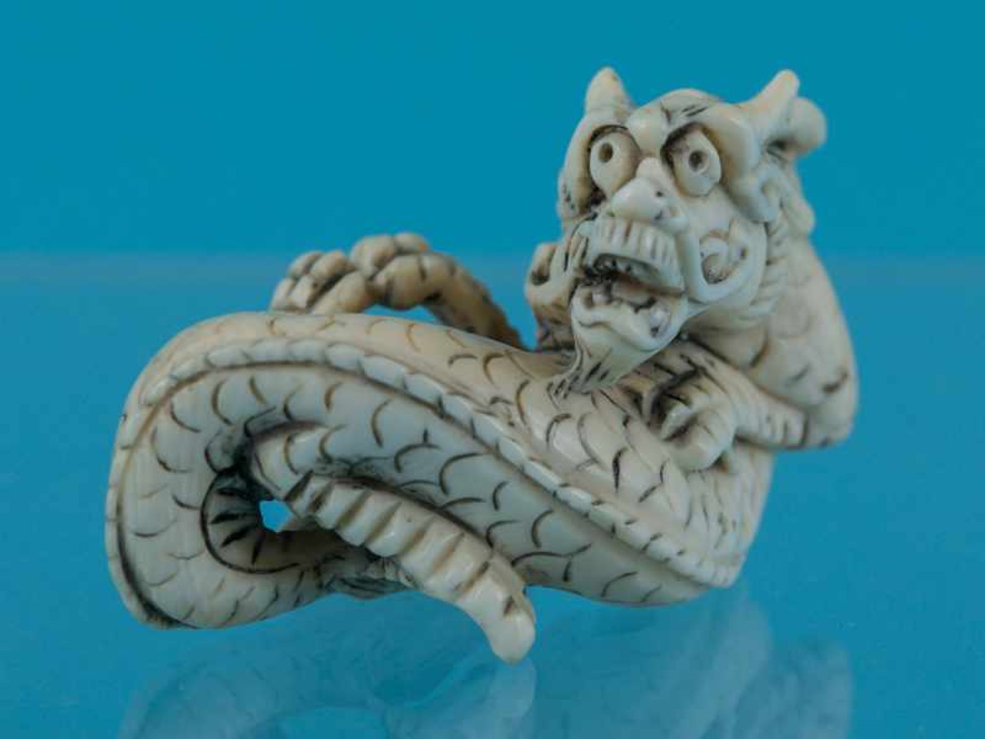 Netsuke, Japan, Meiji-Zeit, um 1900 "liegender Drache". Elfenbein. Fein gravierter Strukturdekor,