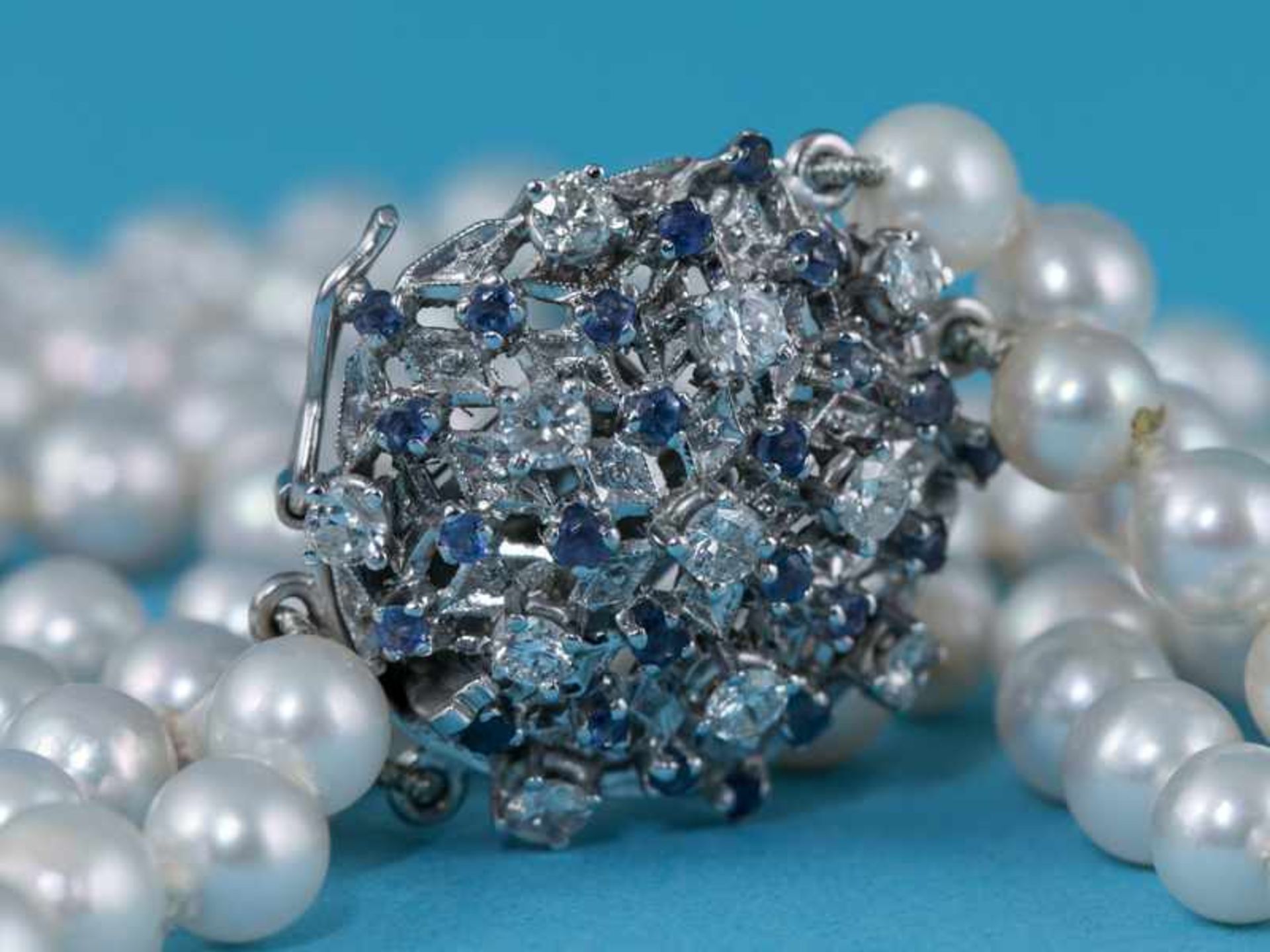 2 rhg. Perlenkette, Schloß mit kleinen Saphiren- und 11 Brillanten, zusammen ca. 0,5 ct, 80- er