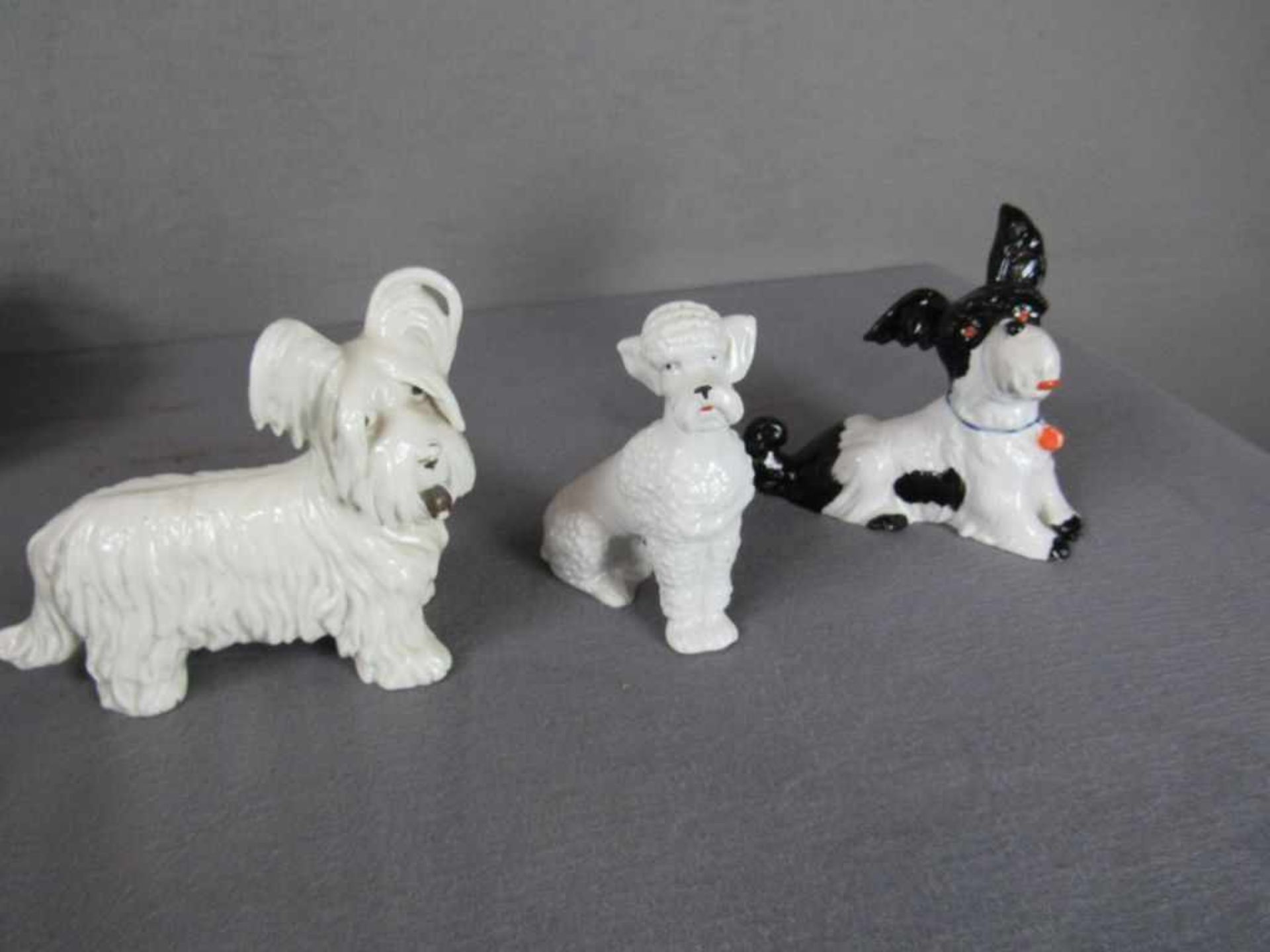 Drei Porzellanfiguren Hunde bis 13cm hoch