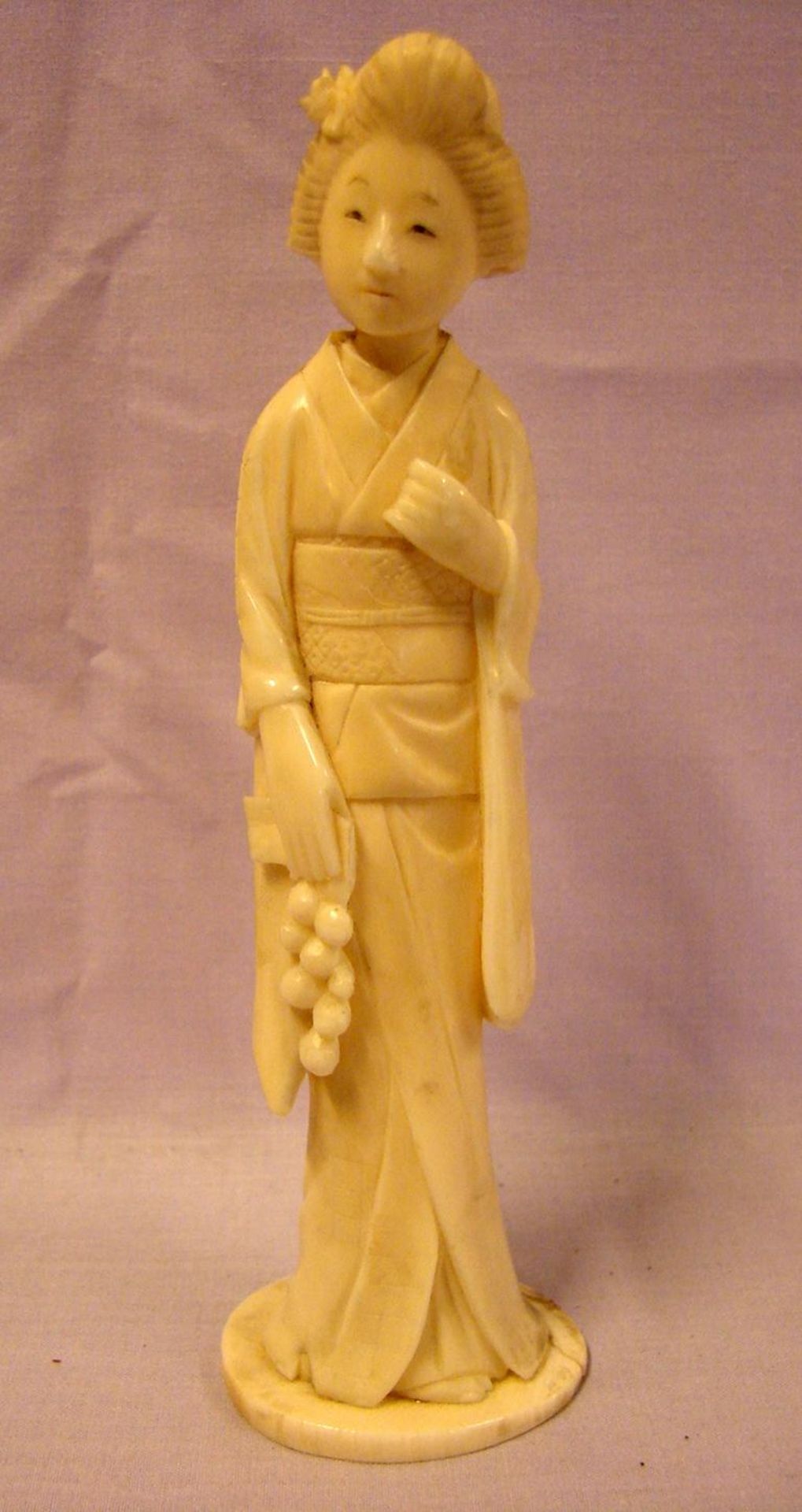 Frau mit Trauben, im Kimono, Bein, geschnitzt, H. ca. 14 cm- - -22.00 % buyer's premium on the