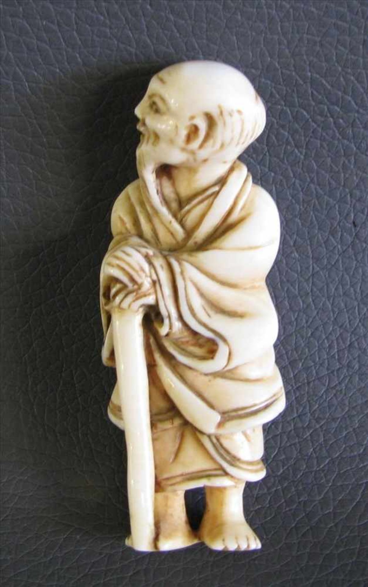 Netsuke, Japan, 19. Jahrhundert, "Alter Mann mit Stab", Elfenbein beschnitzt, 6 x 2 cm.