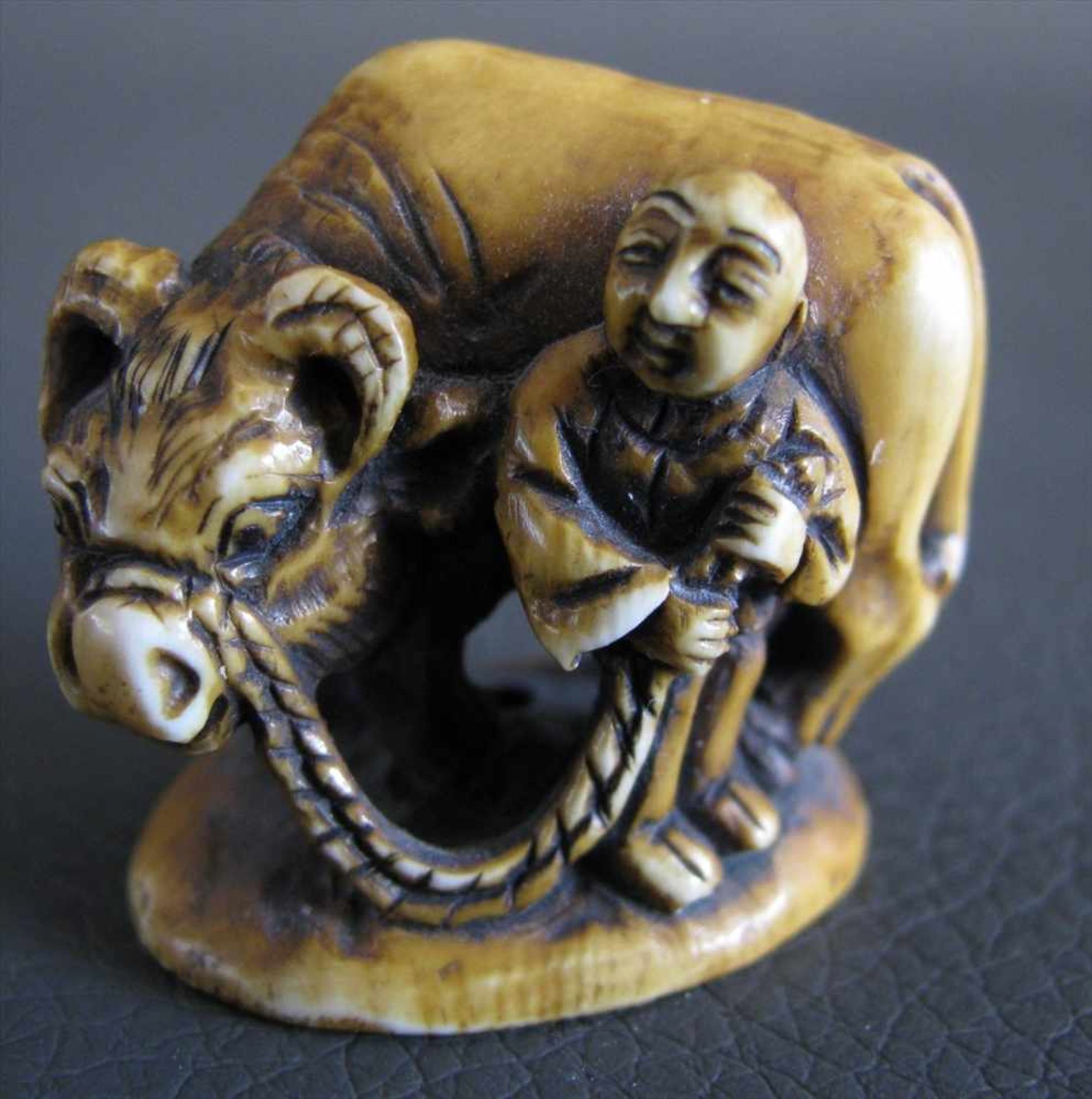 Netsuke, Japan, 19. Jahrhundert, "Bauer mit Ochse", Elfenbein beschnitzt, sign., 2,5 x 2,8 cm.