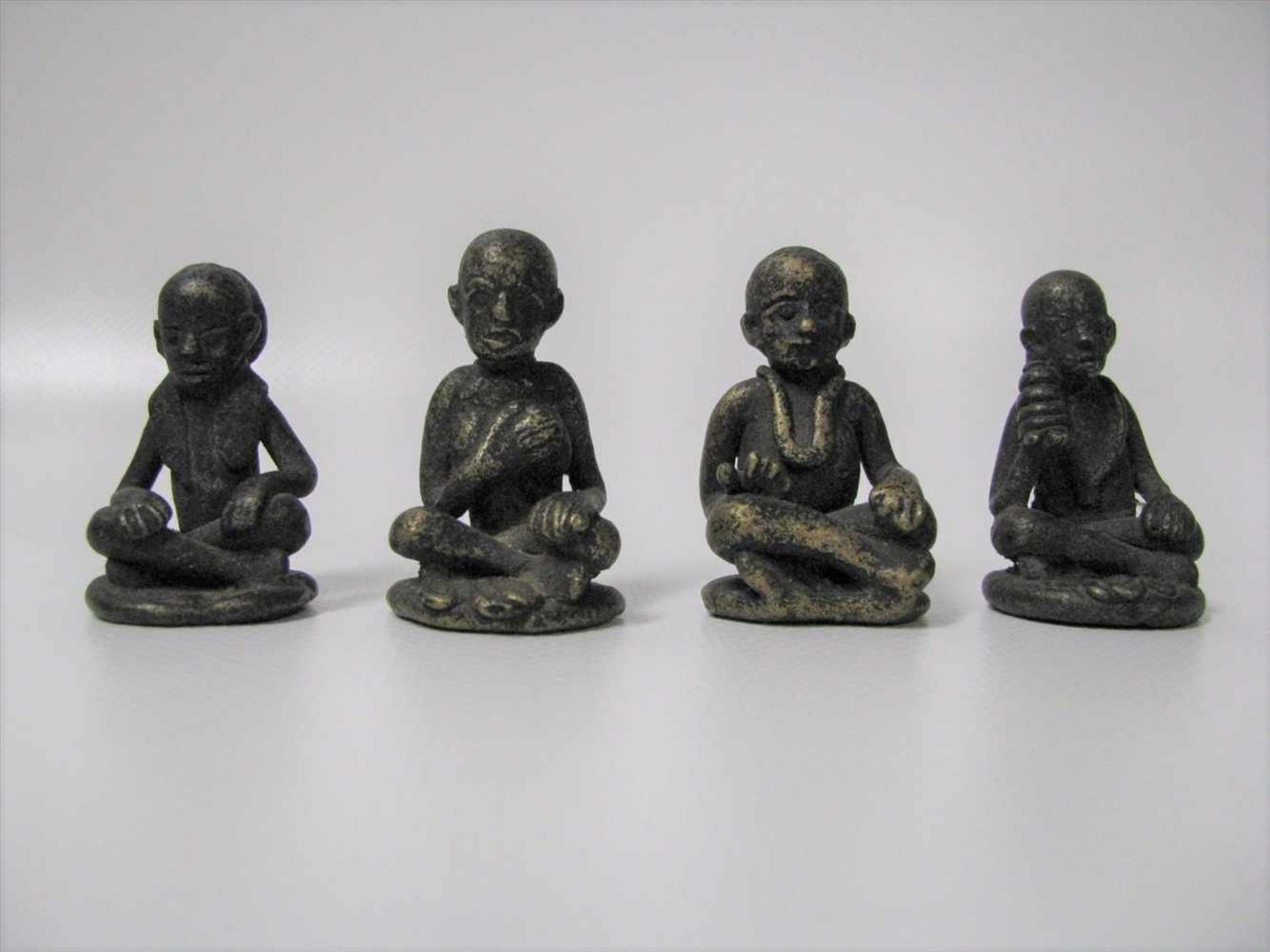 4 sitzende Mönche, Tibet/Nepal, um 1900, Bronze, h 4,5 cm, d 3 cm.