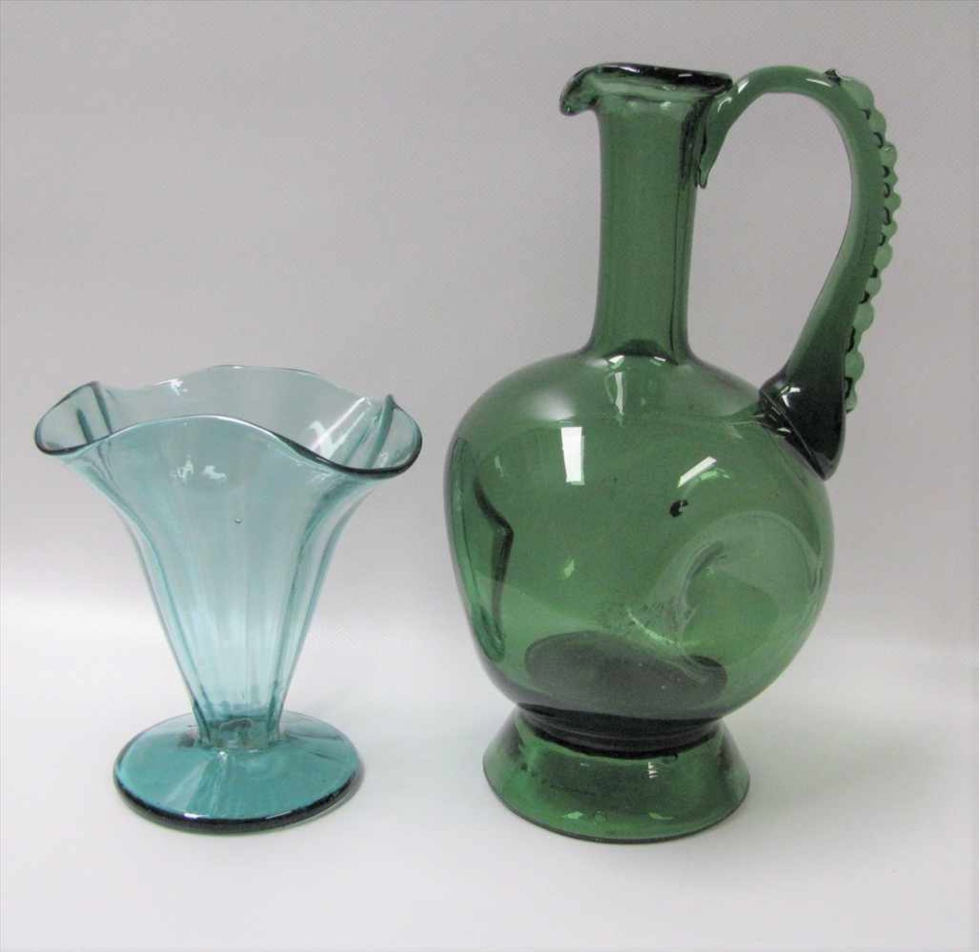Vase und Henkelkrug, grünliches Glas, Abriss, h 16/29 cm.