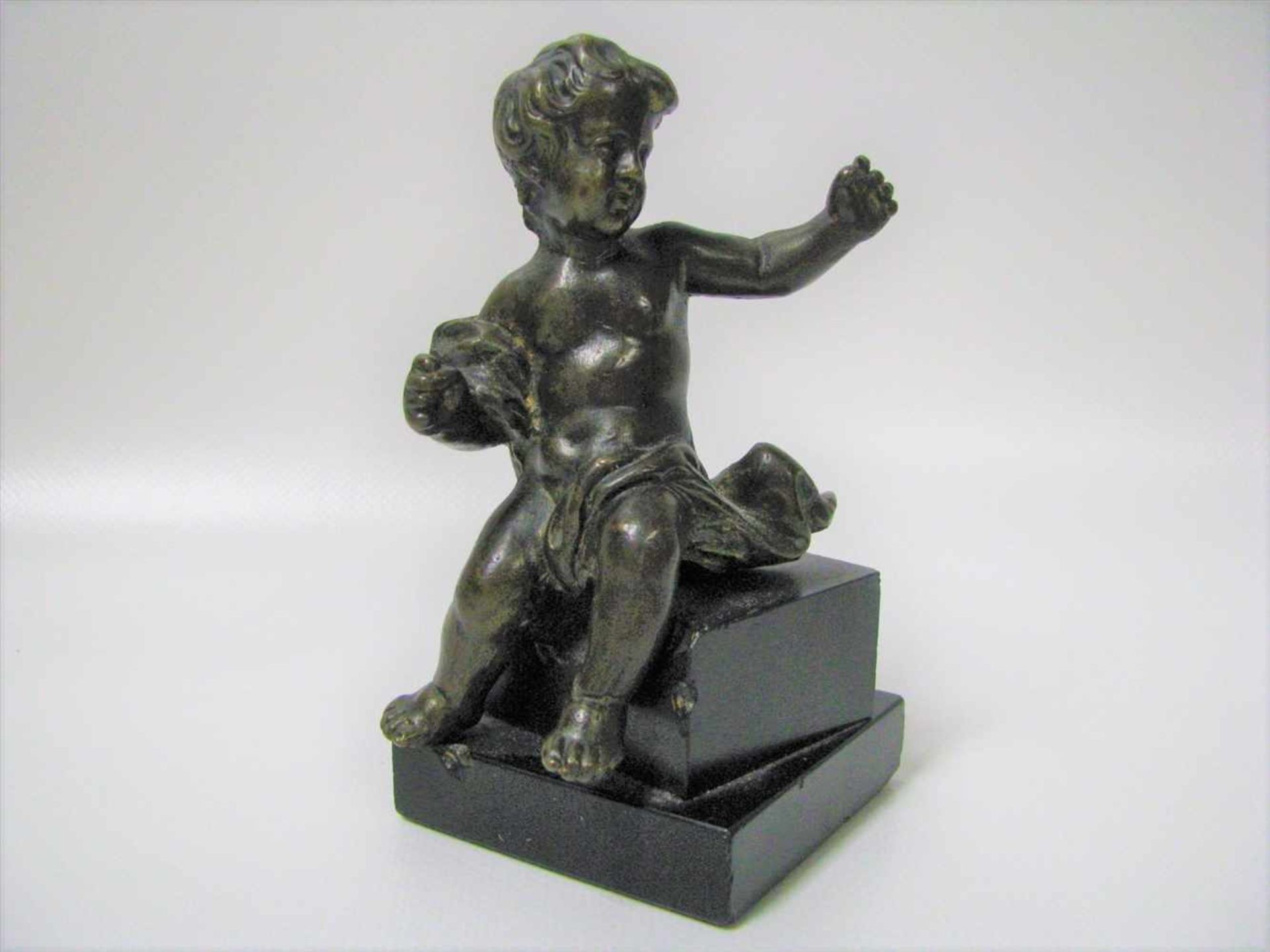Sitzender Putto, 18./19. Jahrhundert, Bronze, h 11,5 cm, d 8 cm.