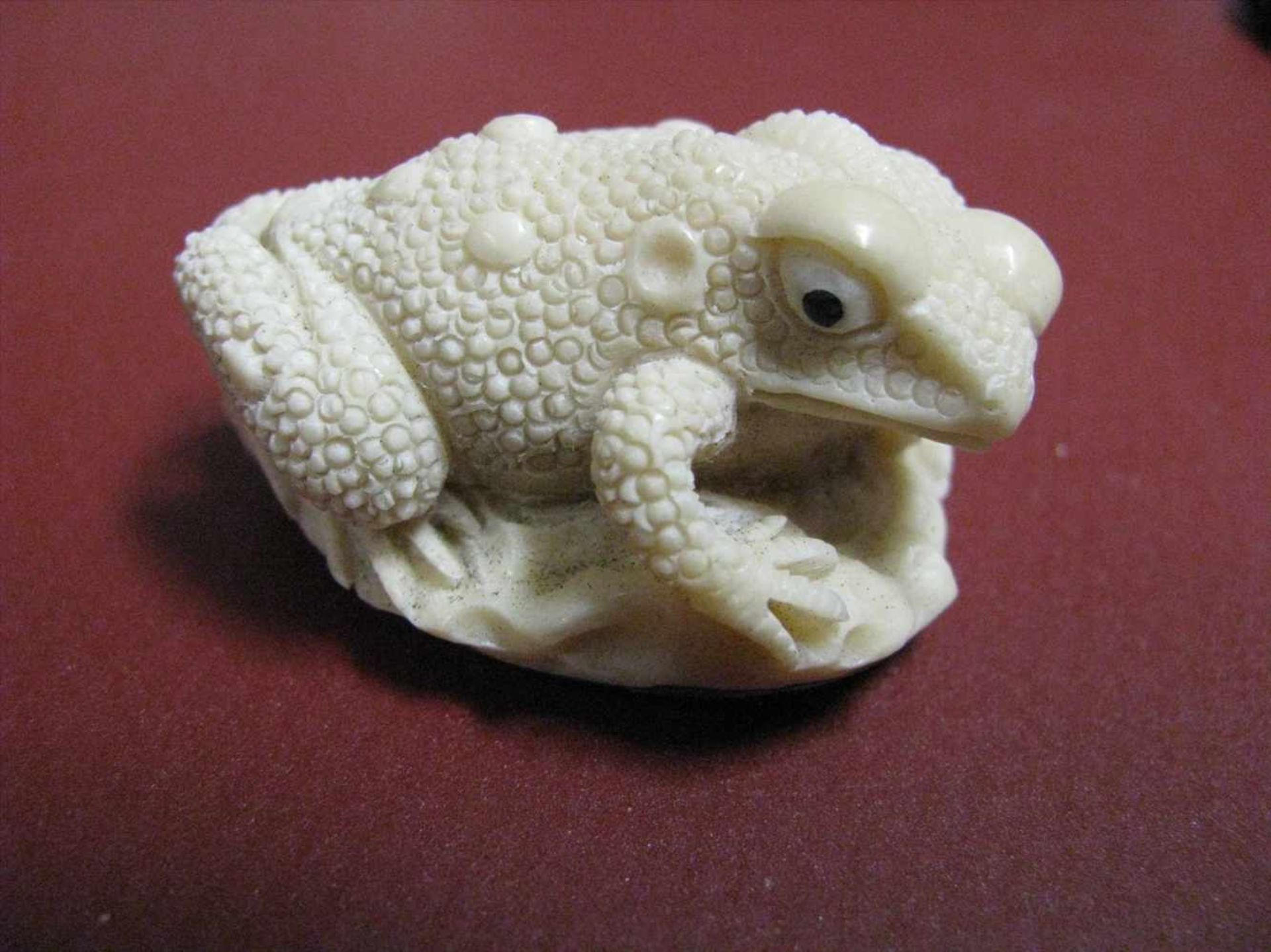 Frosch, wohl Südamerika, Taguanuss/Steinnuss beschnitzt, 2 x 4,5 x 3 cm.